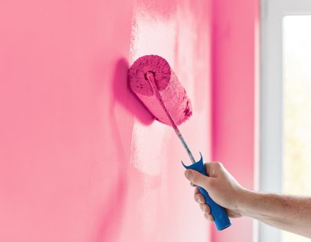 Male hand painting wall with paint roller. Painting apartment, r Male hand painting wall with paint roller. Painting apartment, renovating with pink color paint